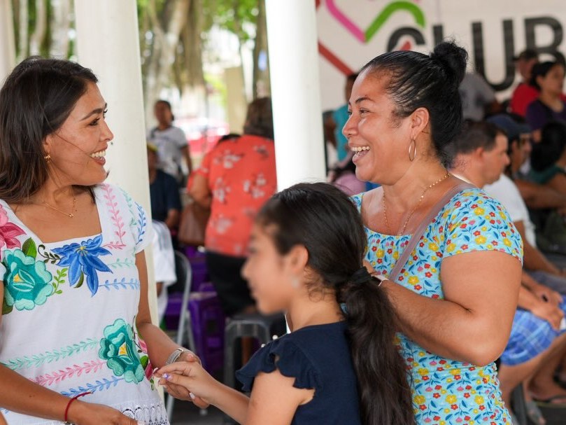 Mirella ríe con vecinas y una niña bajo la lona de Club Corazón en una colonia de Playa del Carmen